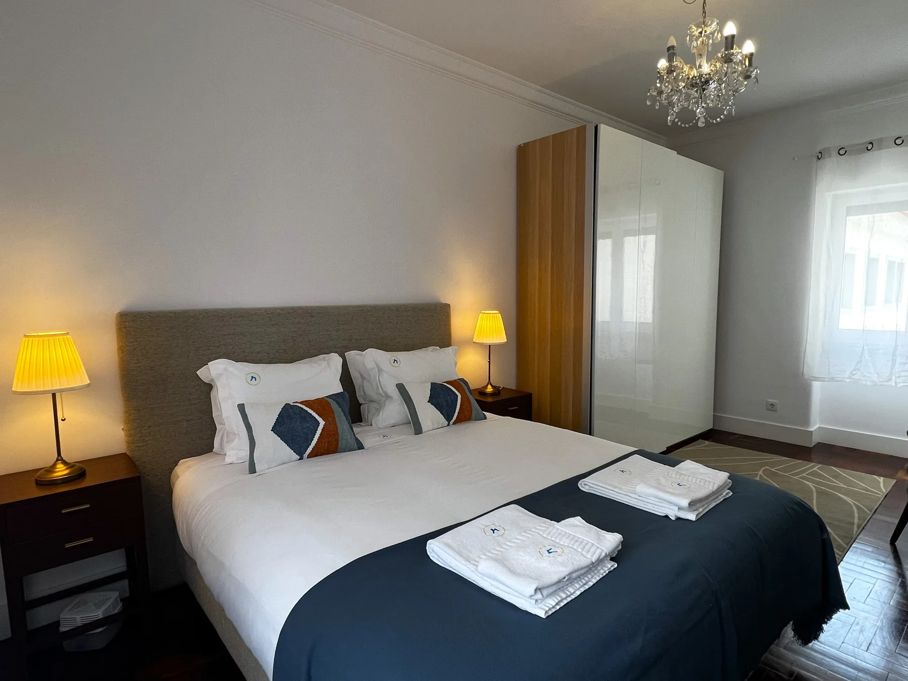 Un dormitorio con una cama doble, lámparas de mesilla y un armario.