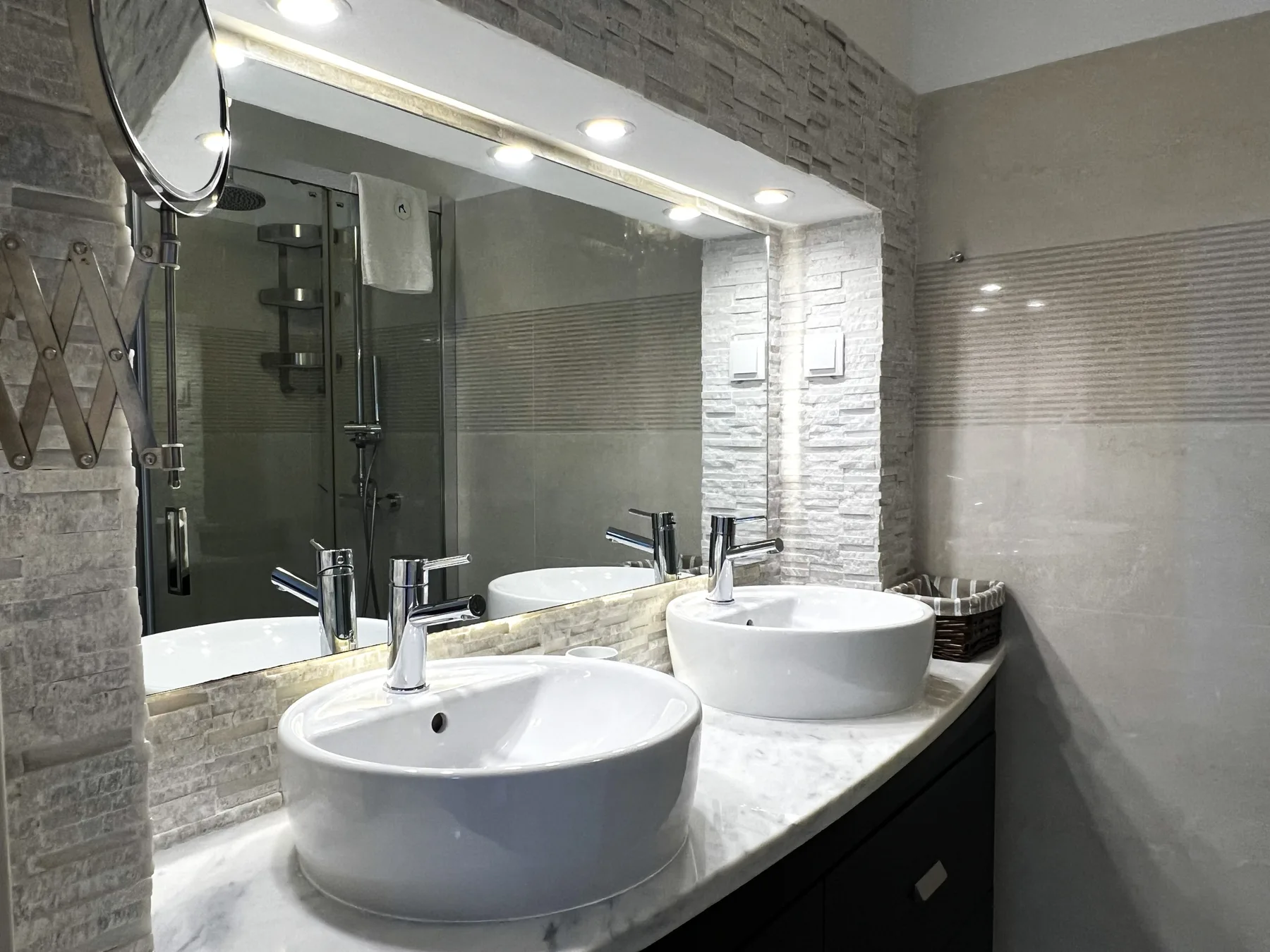 Un mueble de baño con dos lavabos blancos sobre encimera y un espejo grande.