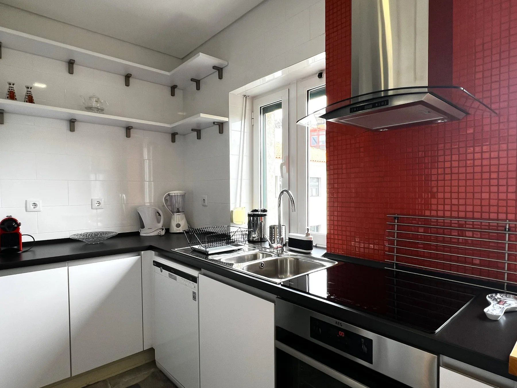 Una cocina moderna con encimeras negras y un salpicadero de azulejos rojos.