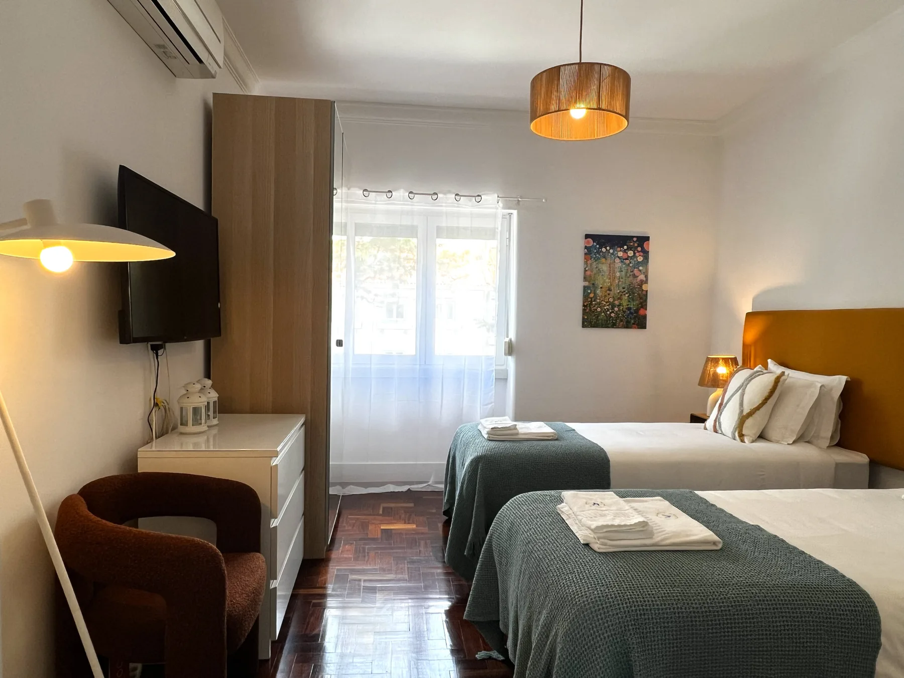 Dormitorio con dos camas, cubrecamas verde oscuro y una ventana.