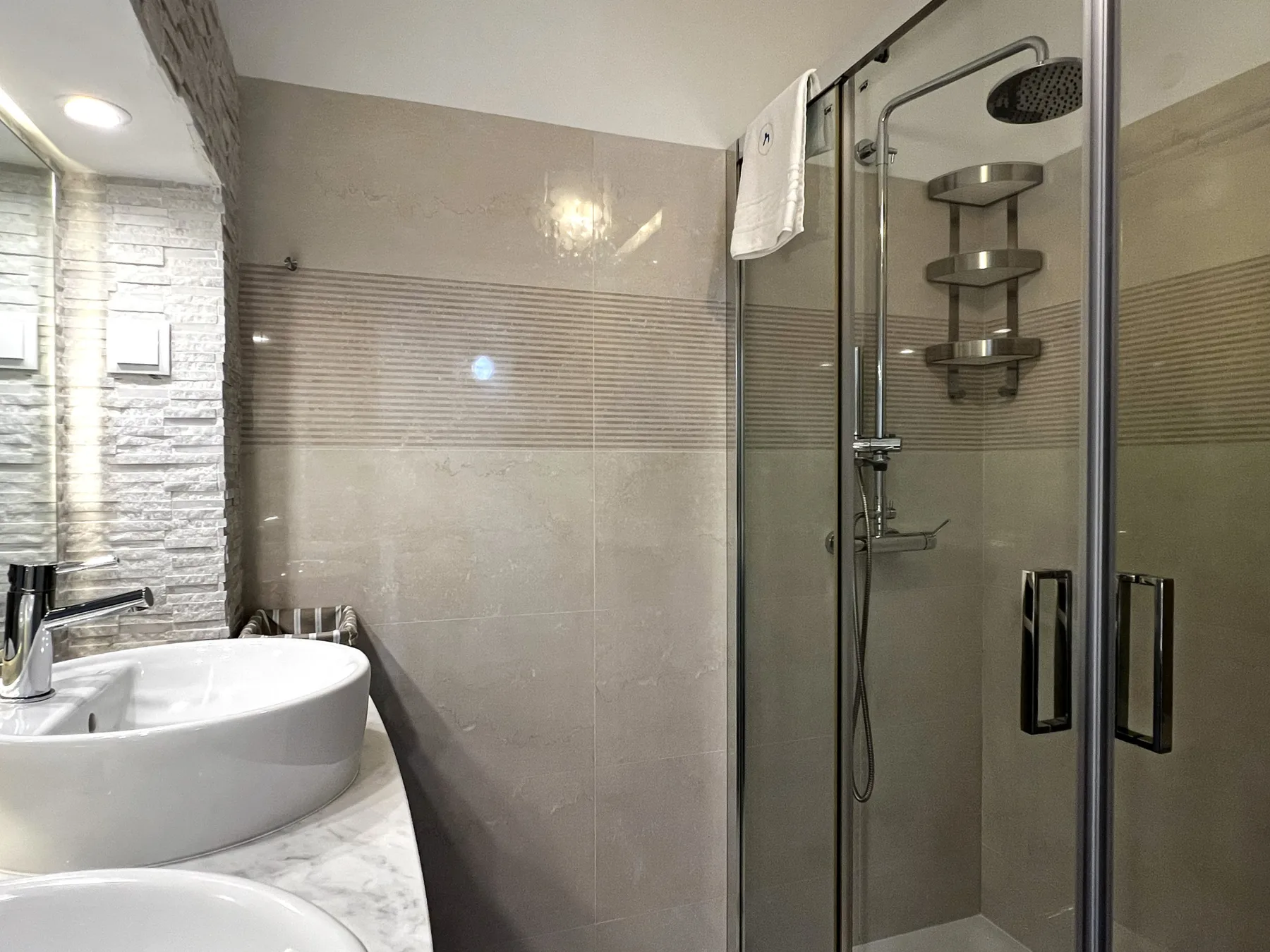 Un baño con un lavabo junto a una ducha con mampara de vidrio.