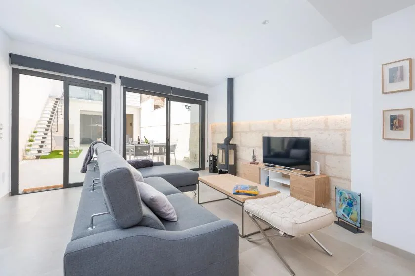 A bright living room with seating, a television, and glass doors opening to a patio.