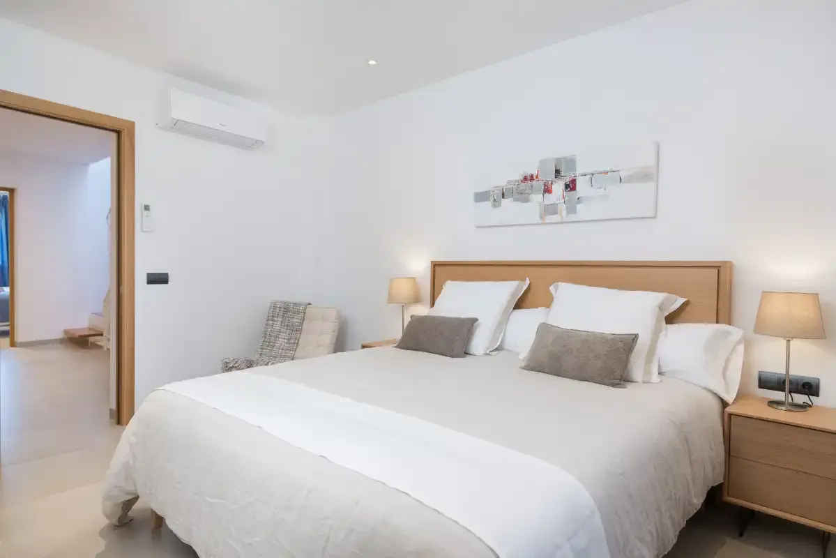 A bright bedroom with a large bed and bedside lamps.