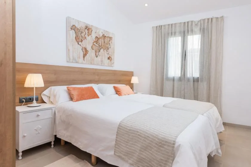 A bedroom with a neatly made bed and a world map artwork above the headboard.