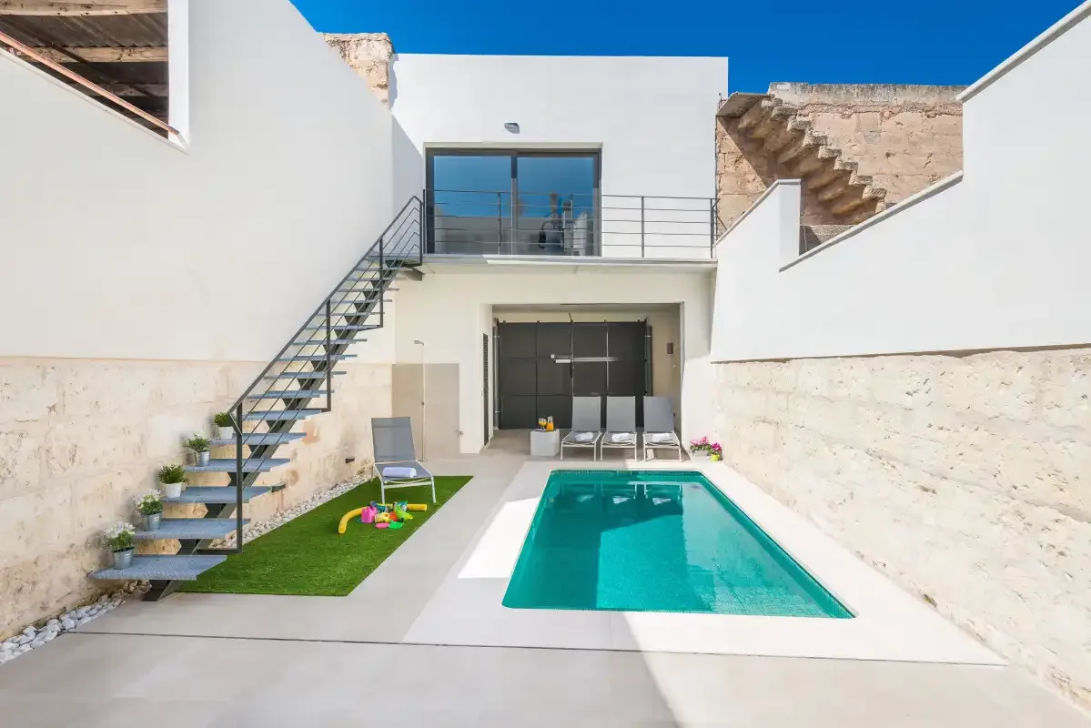 A courtyard pool sits beside an outdoor staircase and seating area.