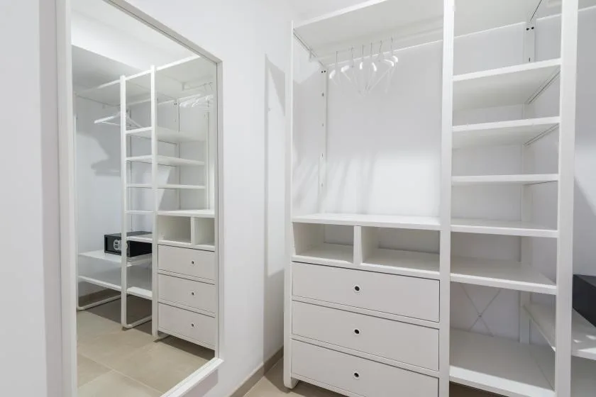 A bright walk-in closet with open shelving, hanging space, and drawers.