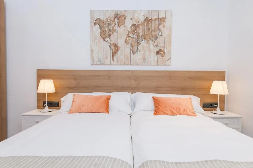 A bedroom with two beds beneath a wooden headboard and a world map artwork.