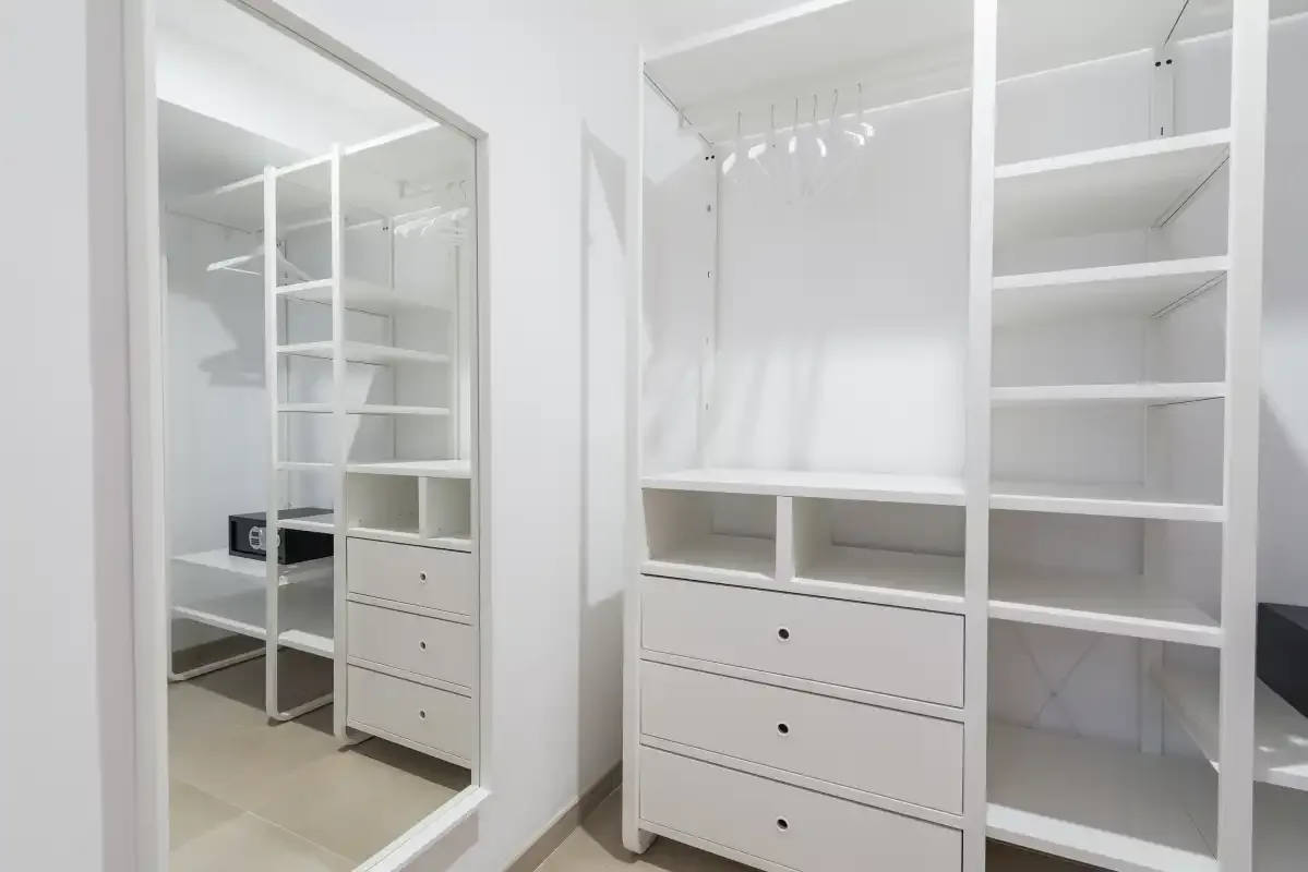 A white walk-in closet with open shelving, drawers, and hanging space.