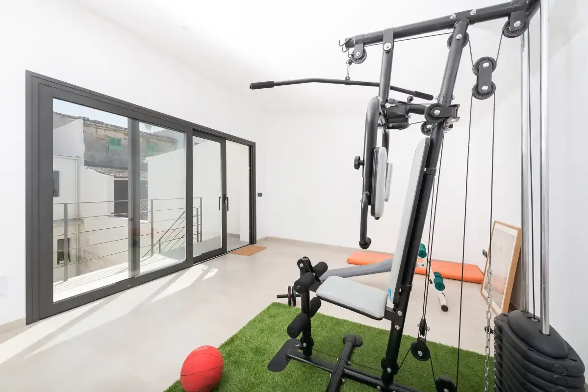 A home gym with exercise equipment beside large glass doors.