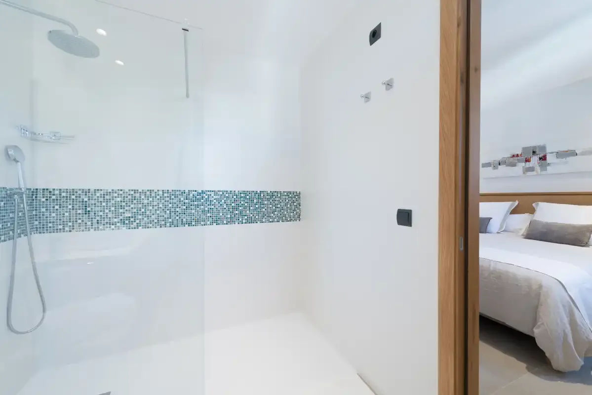 A bright bathroom with a walk-in shower and patterned tile accent.