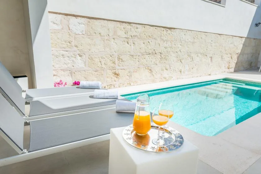 A swimming pool beside lounge seating, with drinks on a small table.