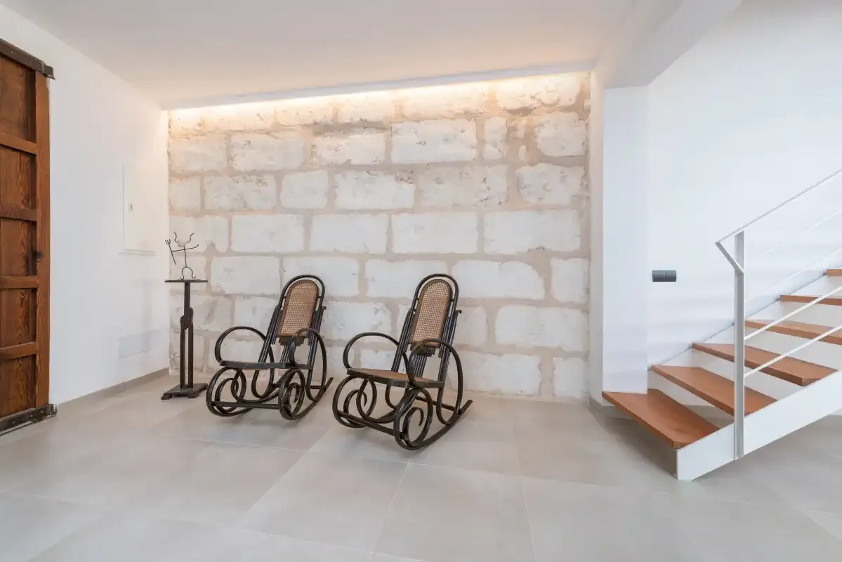 A bright interior sitting area with two rocking chairs beside a staircase.