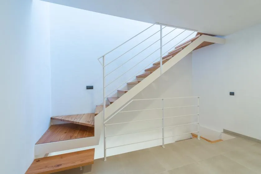A bright interior stairway with wooden steps and a simple metal railing.