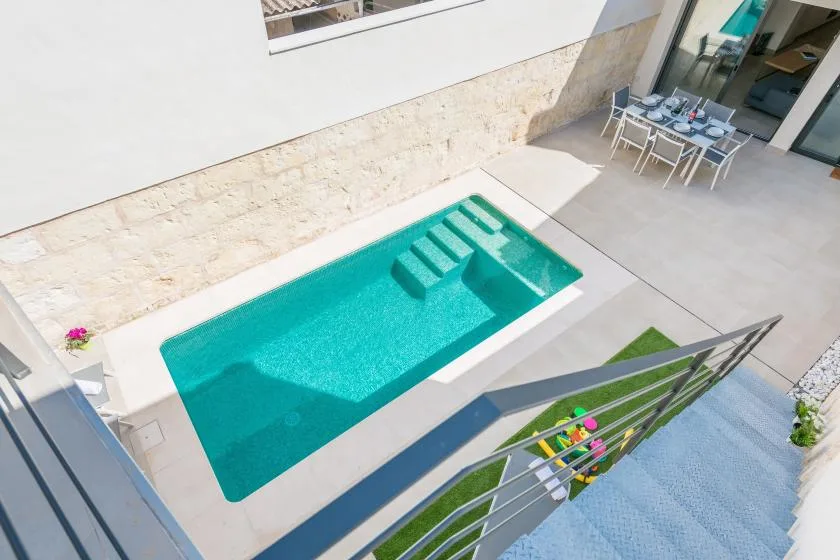 A small outdoor pool sits beside a paved patio with dining seating.