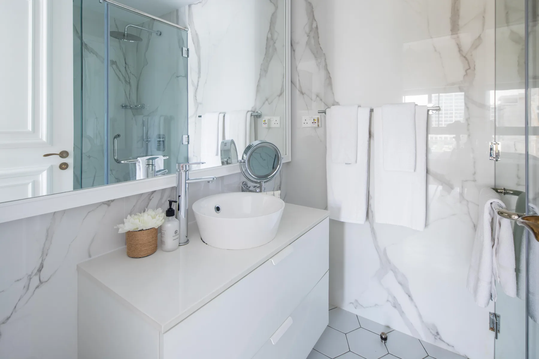 Un baño luminoso con lavabo, mueble de tocador y ducha de vidrio.