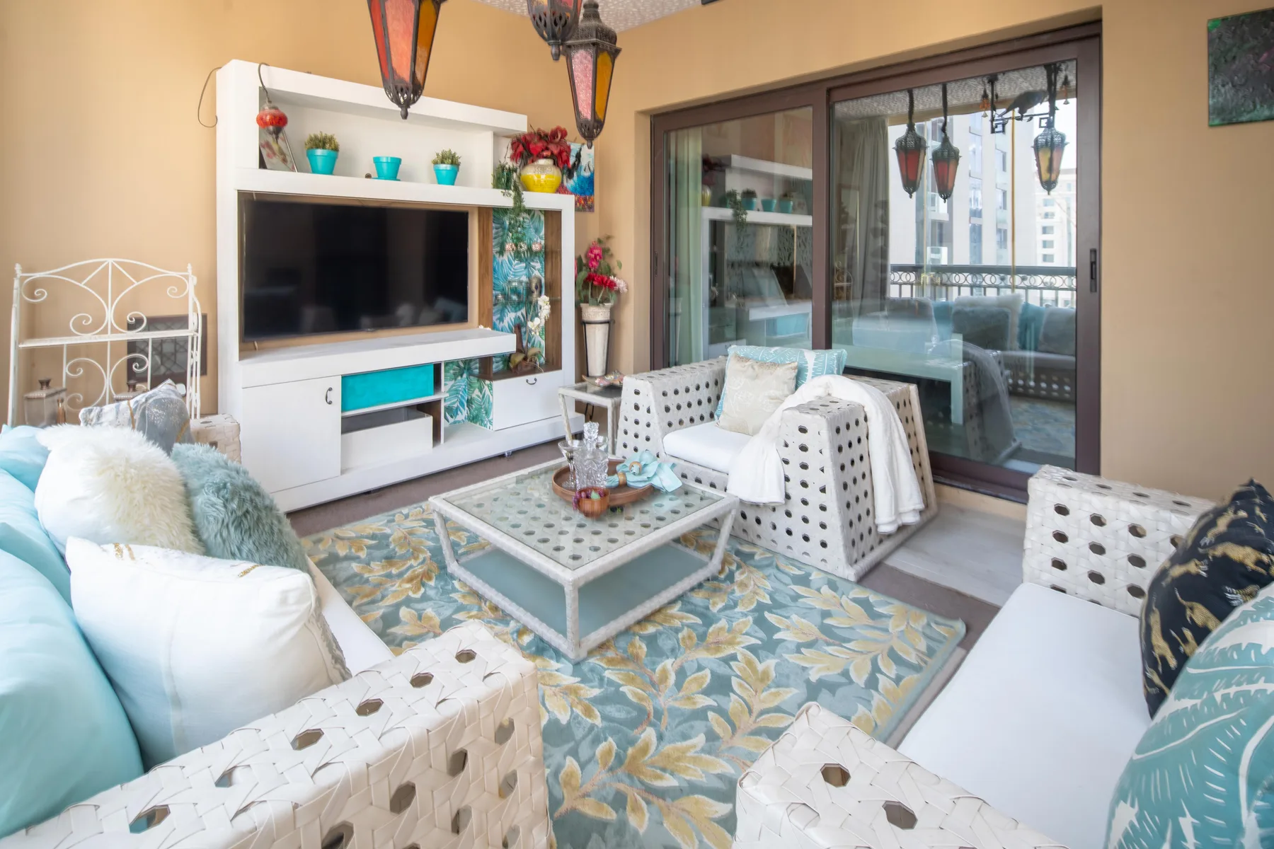 Una sala de estar con asientos estampados, una mesa de centro y puertas corredizas de vidrio.