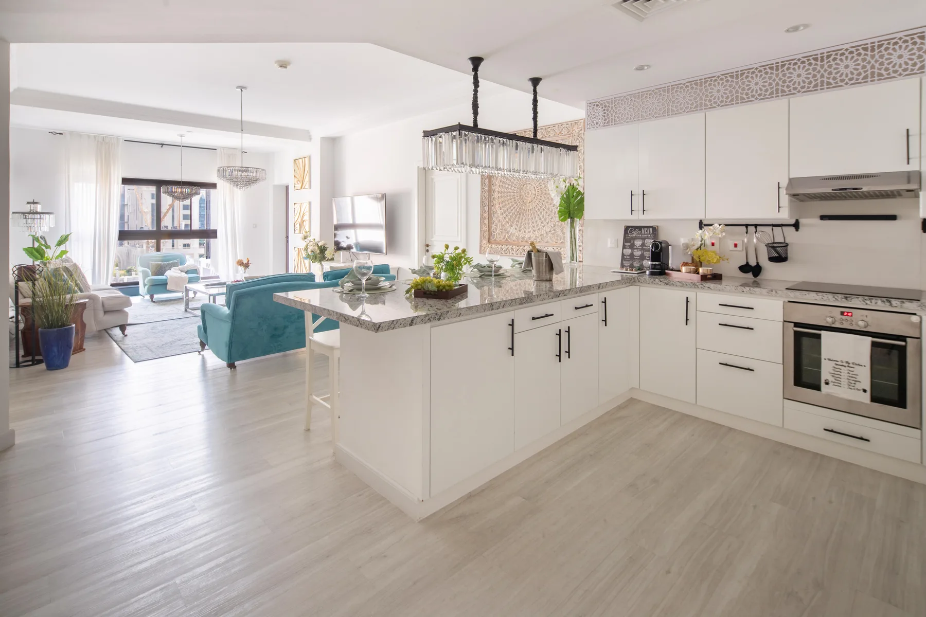 Una luminosa cocina abierta al salón, con una isla central y asientos color turquesa.