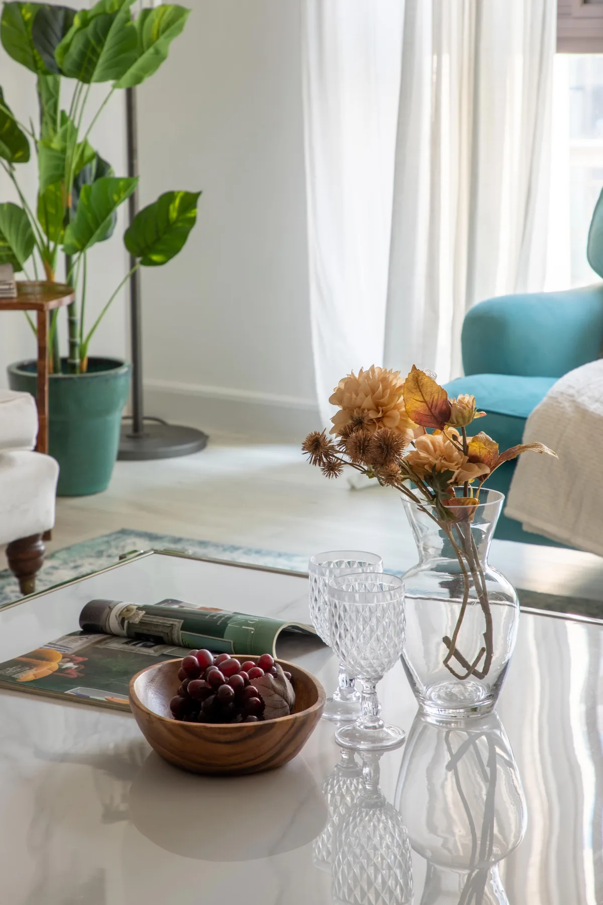 Una sala luminosa con asientos, una mesa de centro de vidrio y flores.