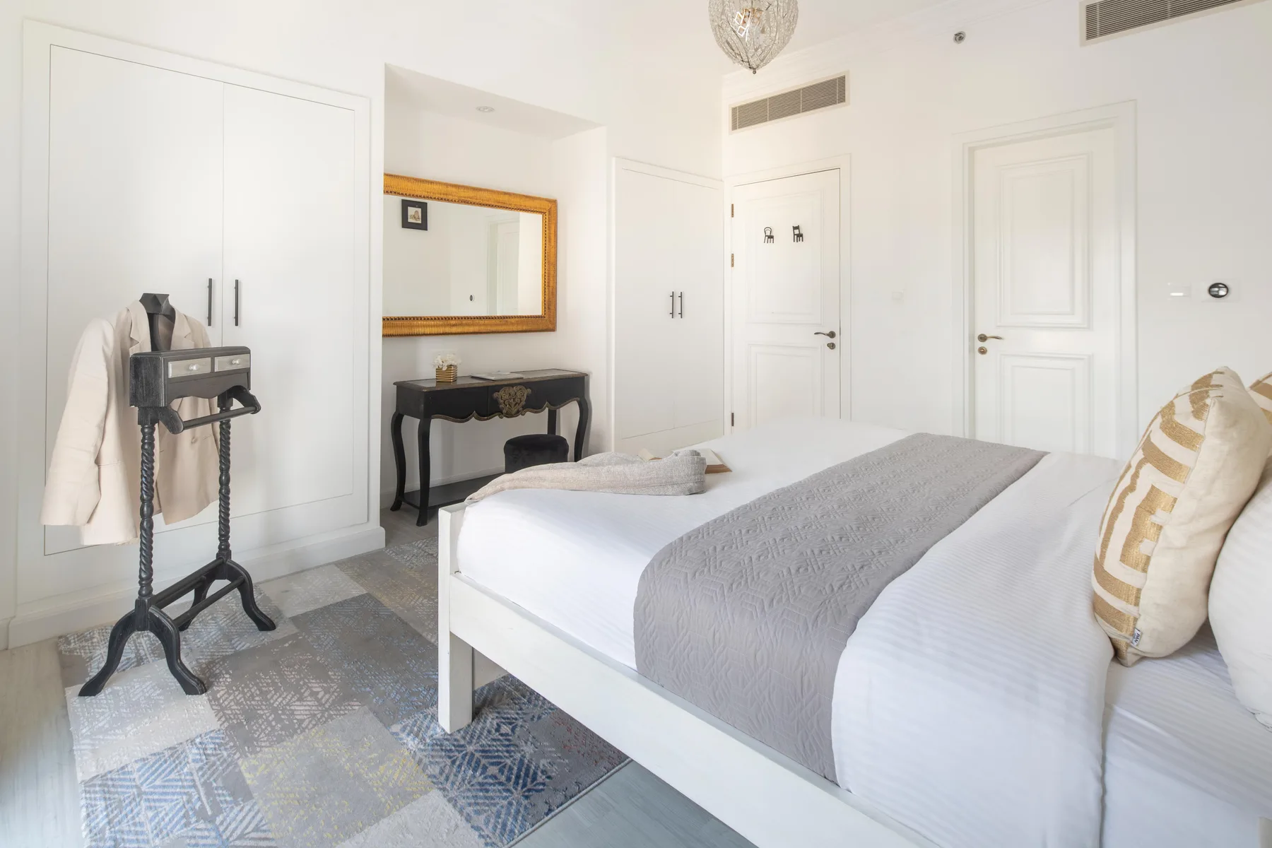 Un dormitorio luminoso con una cama, una mesa auxiliar y un espejo de pared.