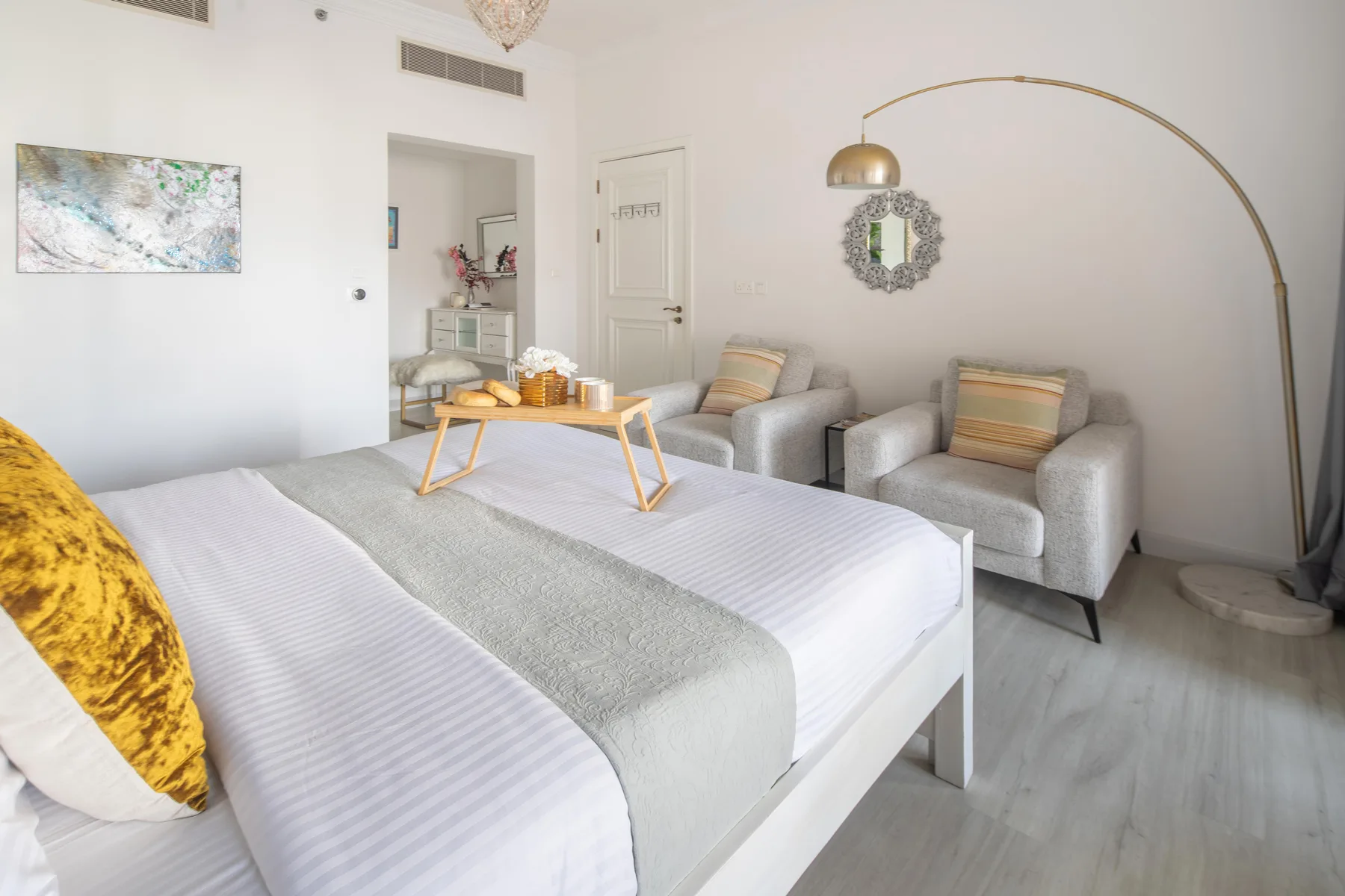 Un dormitorio luminoso con una cama grande y dos sillones tapizados.