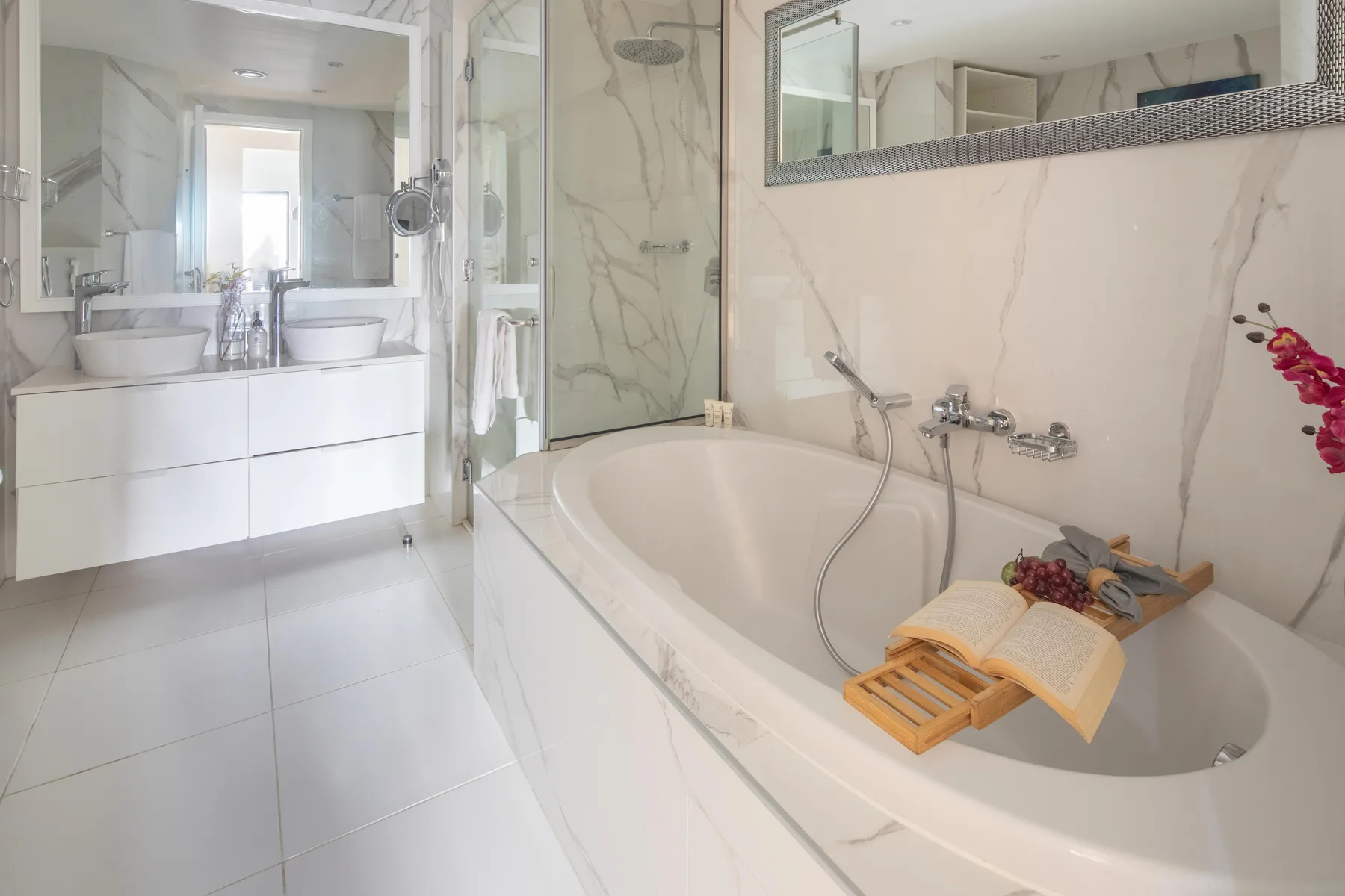 Un baño luminoso con bañera y un lavabo con dos cuencos.