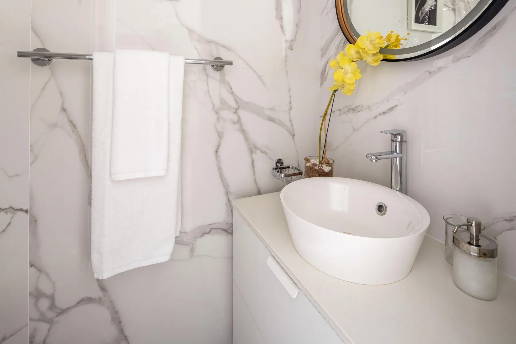 Un lavabo de baño con una pila blanca sobrepuesta y una toalla colgada cerca.