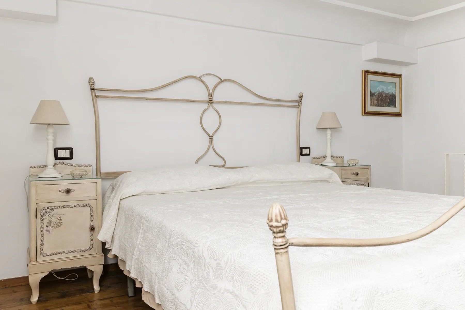 Un dormitorio luminoso con una cama grande, mesitas de noche y lámparas.