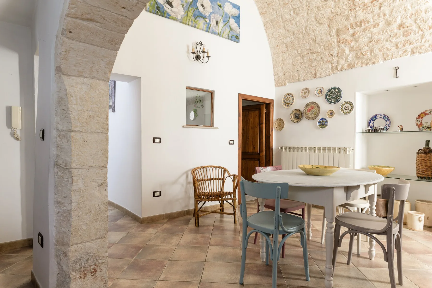 Un comedor con una mesa grande y sillas bajo un arco de piedra.