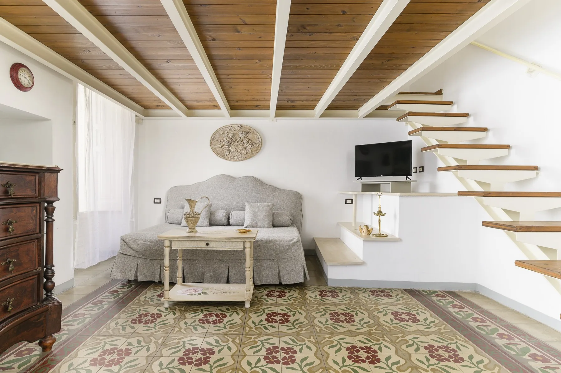 Una sala de estar con sofá, mesa de centro y escalera abierta.