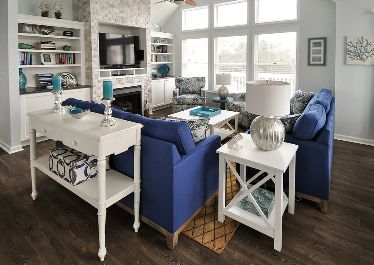 A bright living room with blue seating, a television, and large windows.