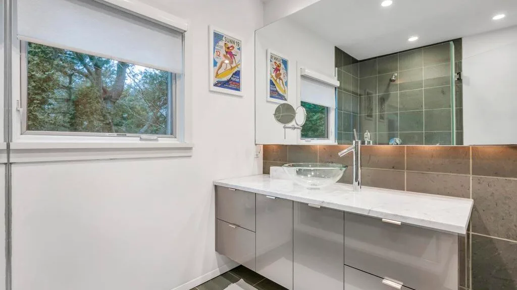 Un baño luminoso con un tocador largo y una ducha con mampara de vidrio.