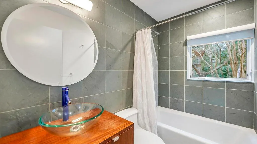 Un baño con bañera, cortina de ducha y lavabo de vidrio.