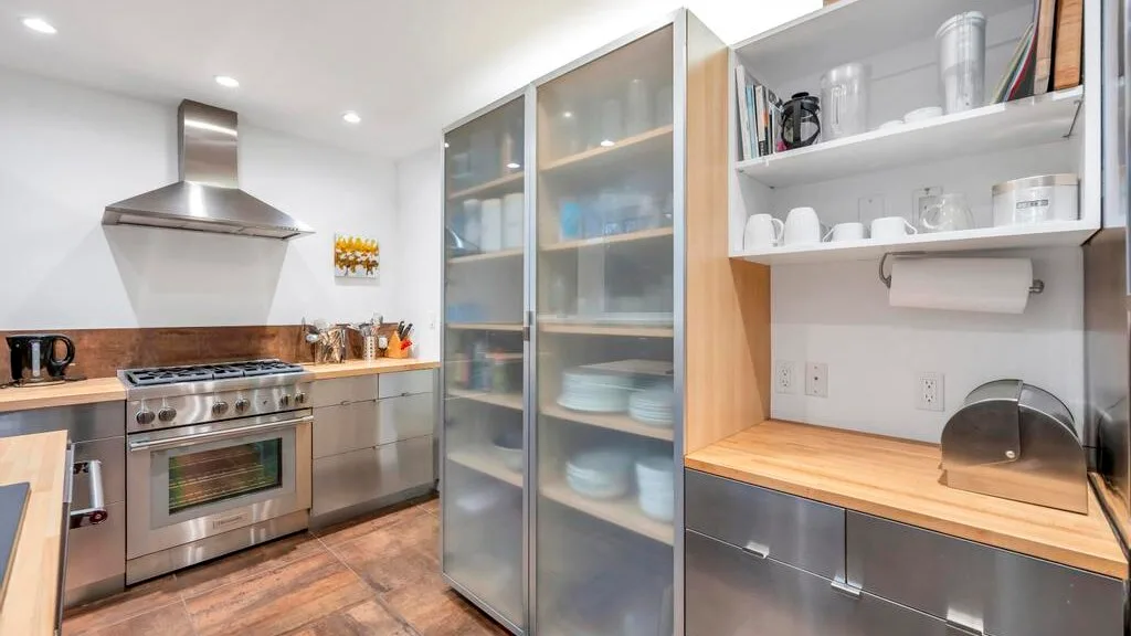 Una cocina luminosa con una estufa de acero inoxidable y gabinetes con puertas de vidrio.