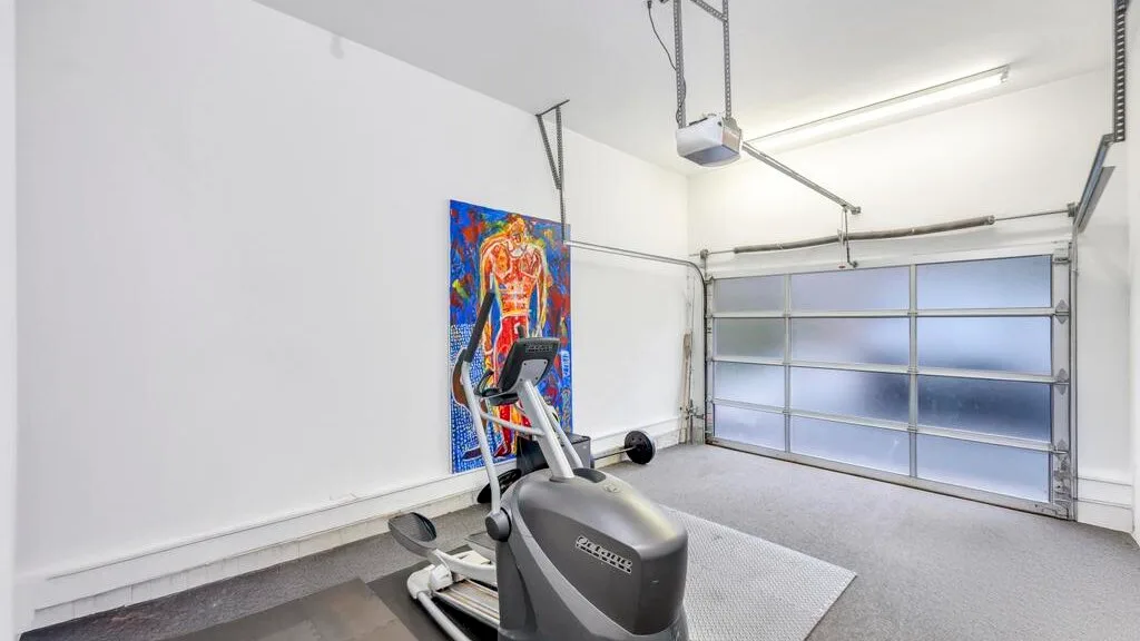 Un gimnasio en casa con una máquina elíptica y arte colorido en la pared.