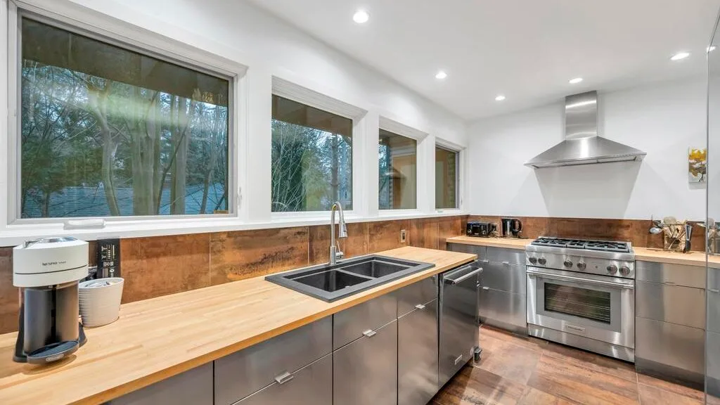 Una cocina moderna con una encimera larga, fregadero y electrodomésticos de acero inoxidable.
