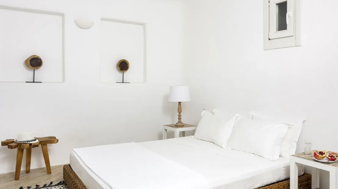 A bright bedroom with a white bed and framed wall art.