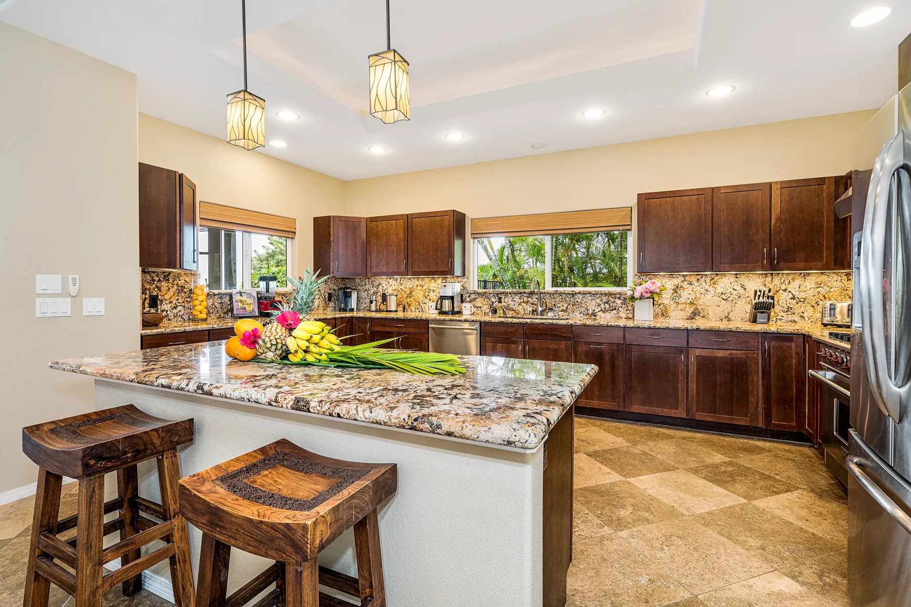 Una cocina luminosa con gabinetes de madera oscura y una isla con cubierta de piedra.
