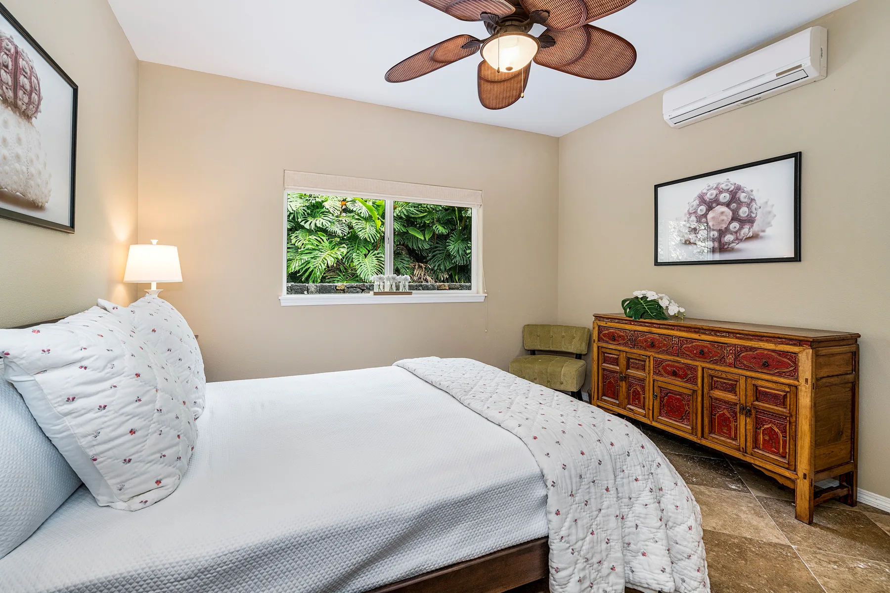 Un dormitorio con una cama, una cómoda de madera y una ventana con vista a la vegetación.
