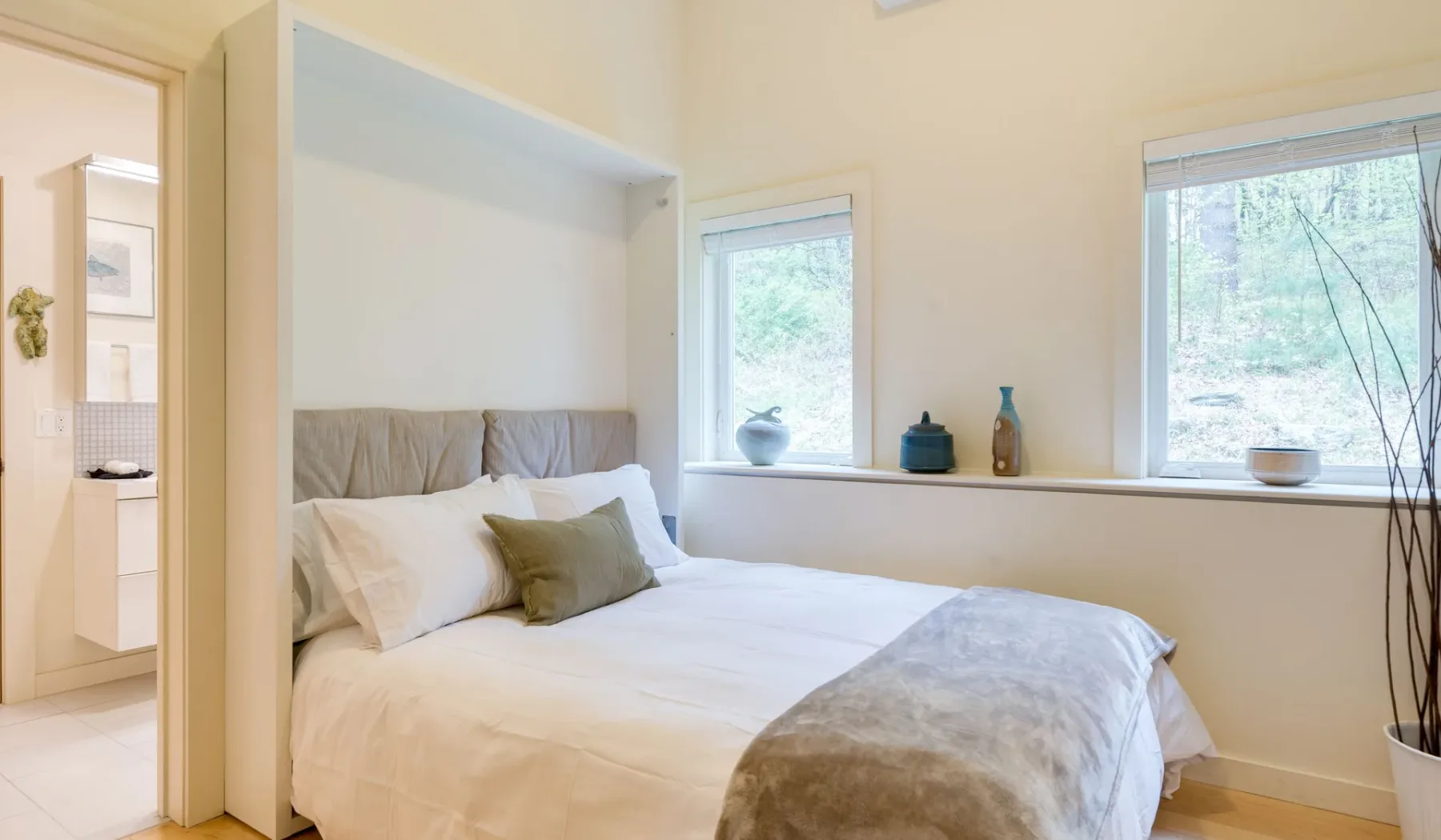 A bright bedroom with a bed beneath two windows.