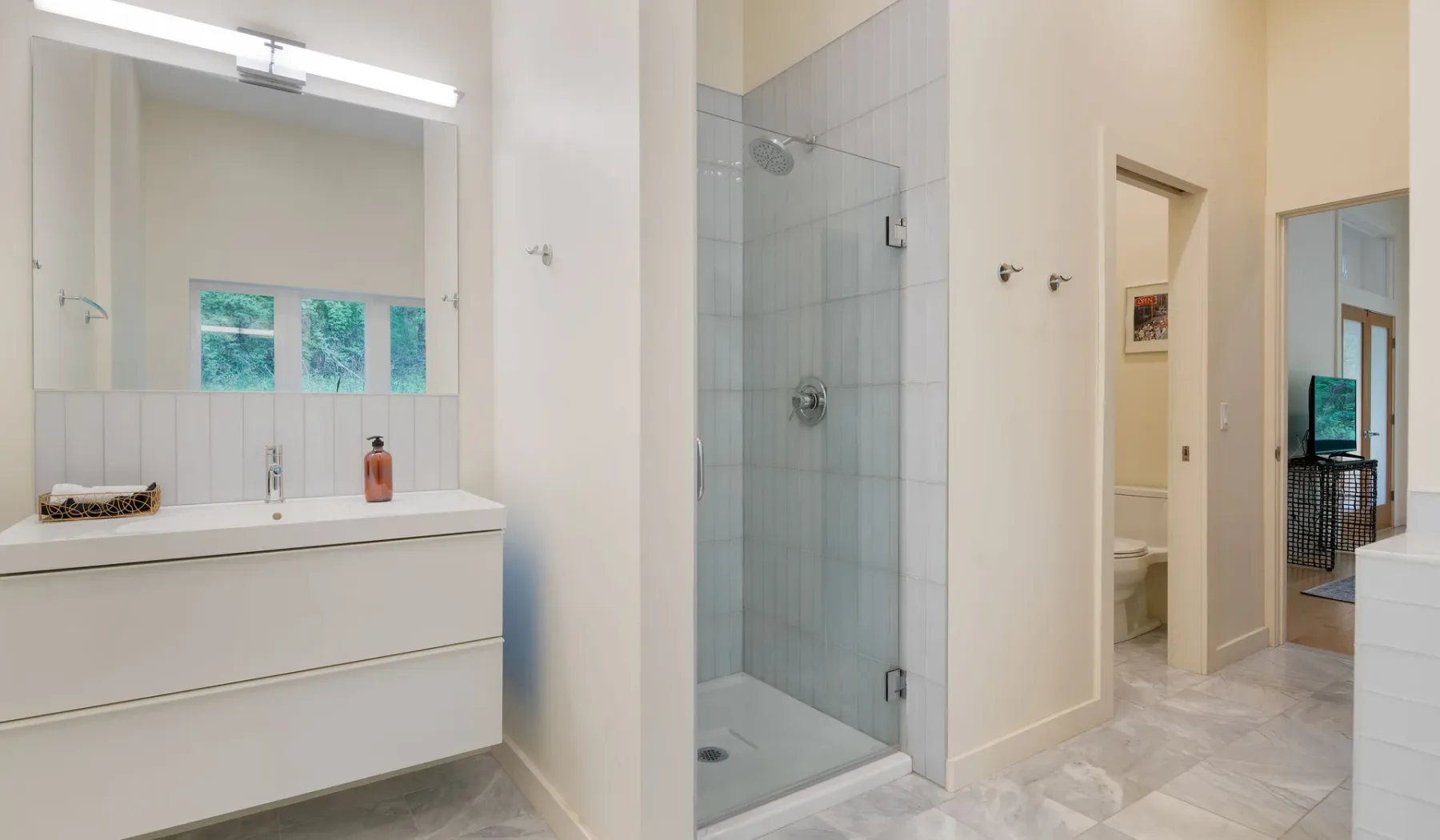 A bright bathroom with a wide vanity and glass shower.