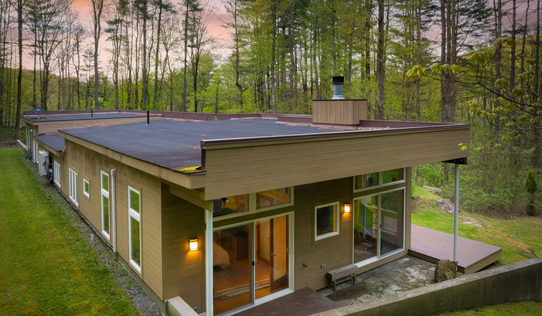 A modern house sits among trees, with a broad flat roof and large windows.