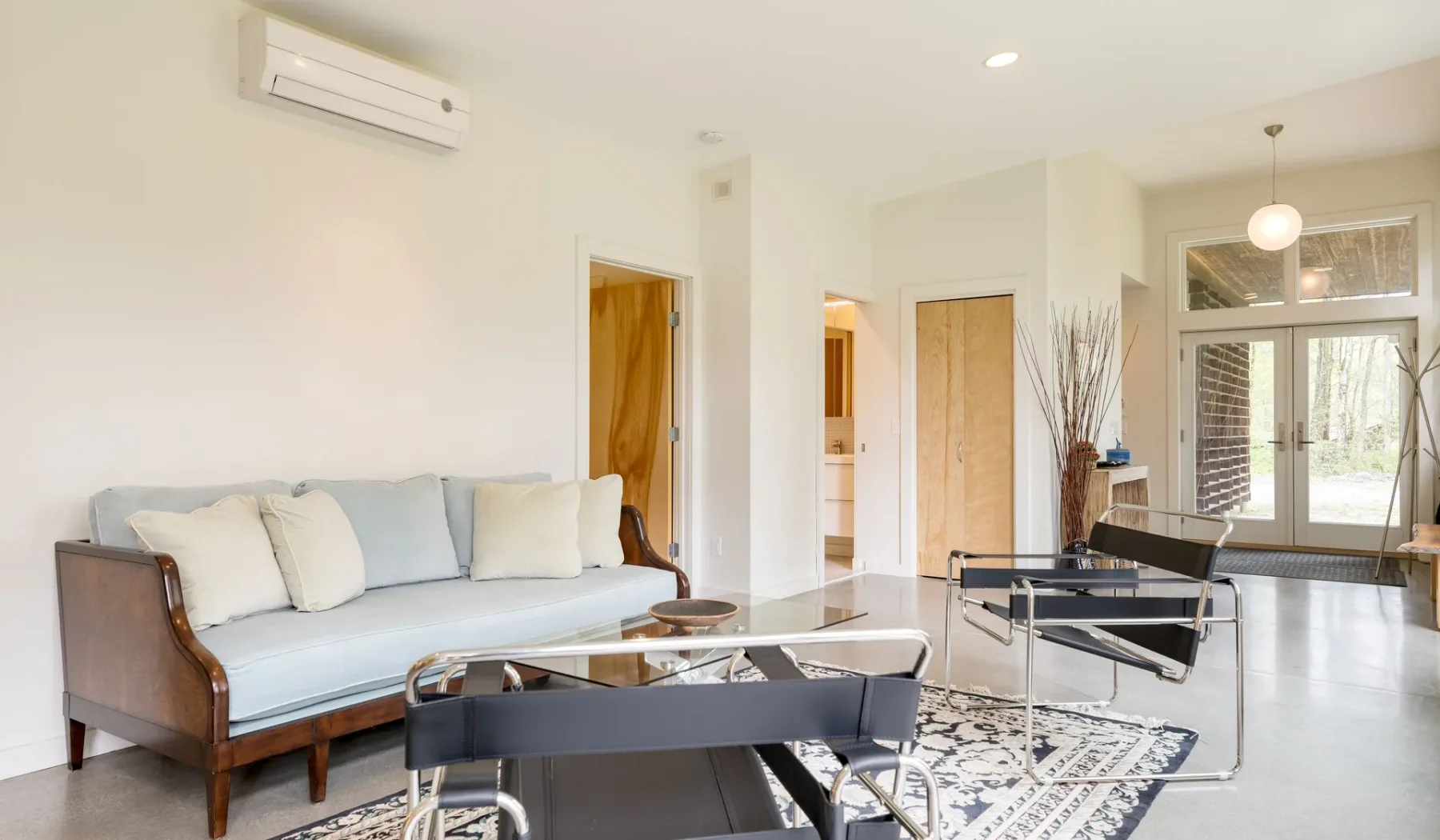 A bright living room with seating and a glass coffee table.