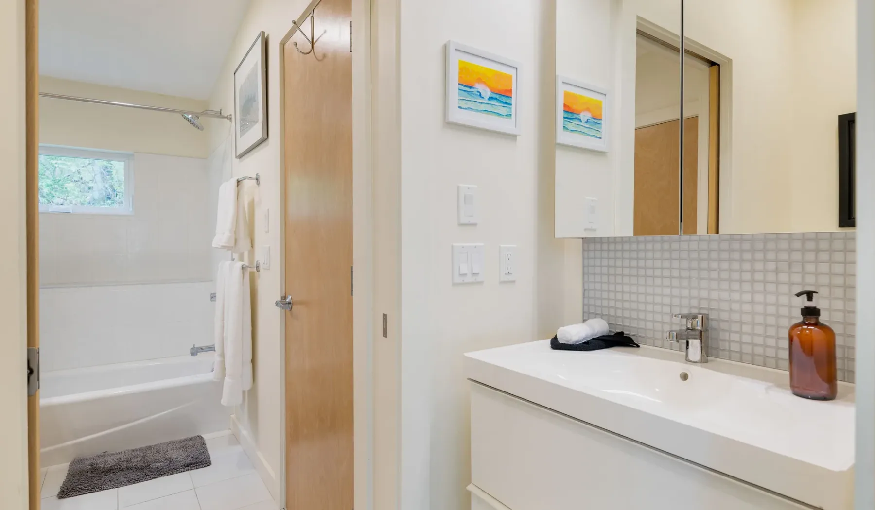 A bathroom vanity with a sink and mirror beside a bathtub.