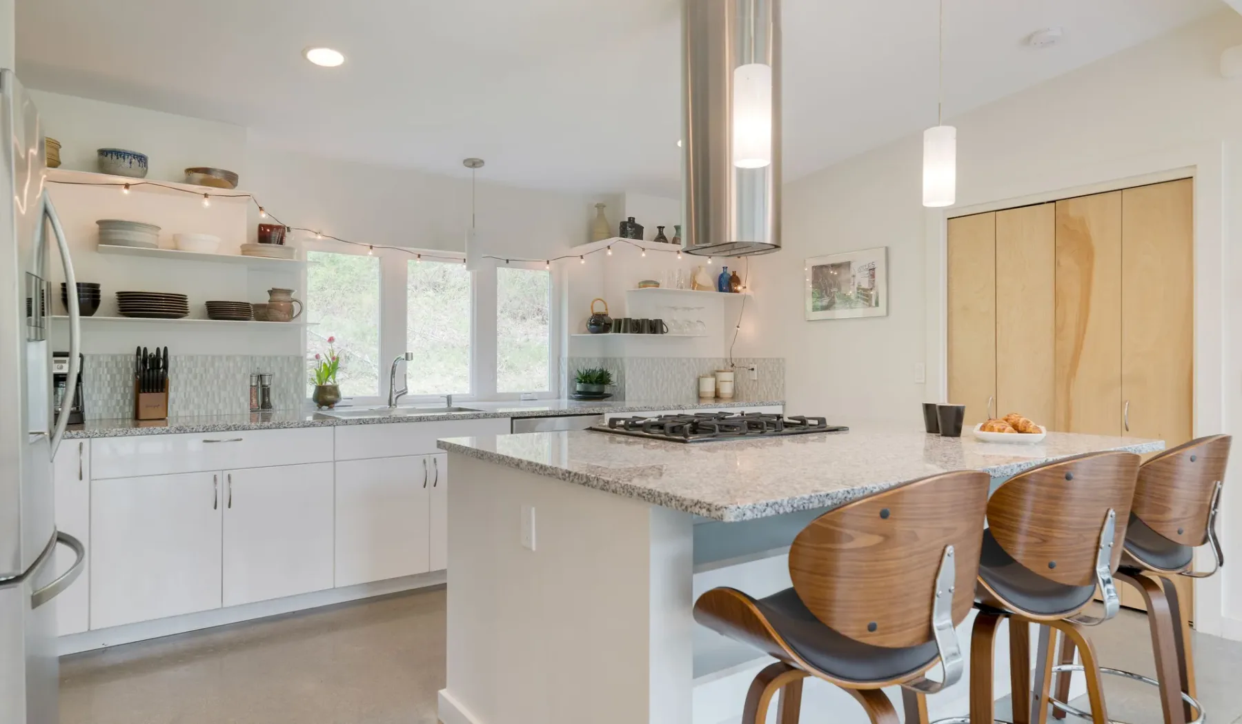 A bright kitchen with white cabinets, a central island, and seating.