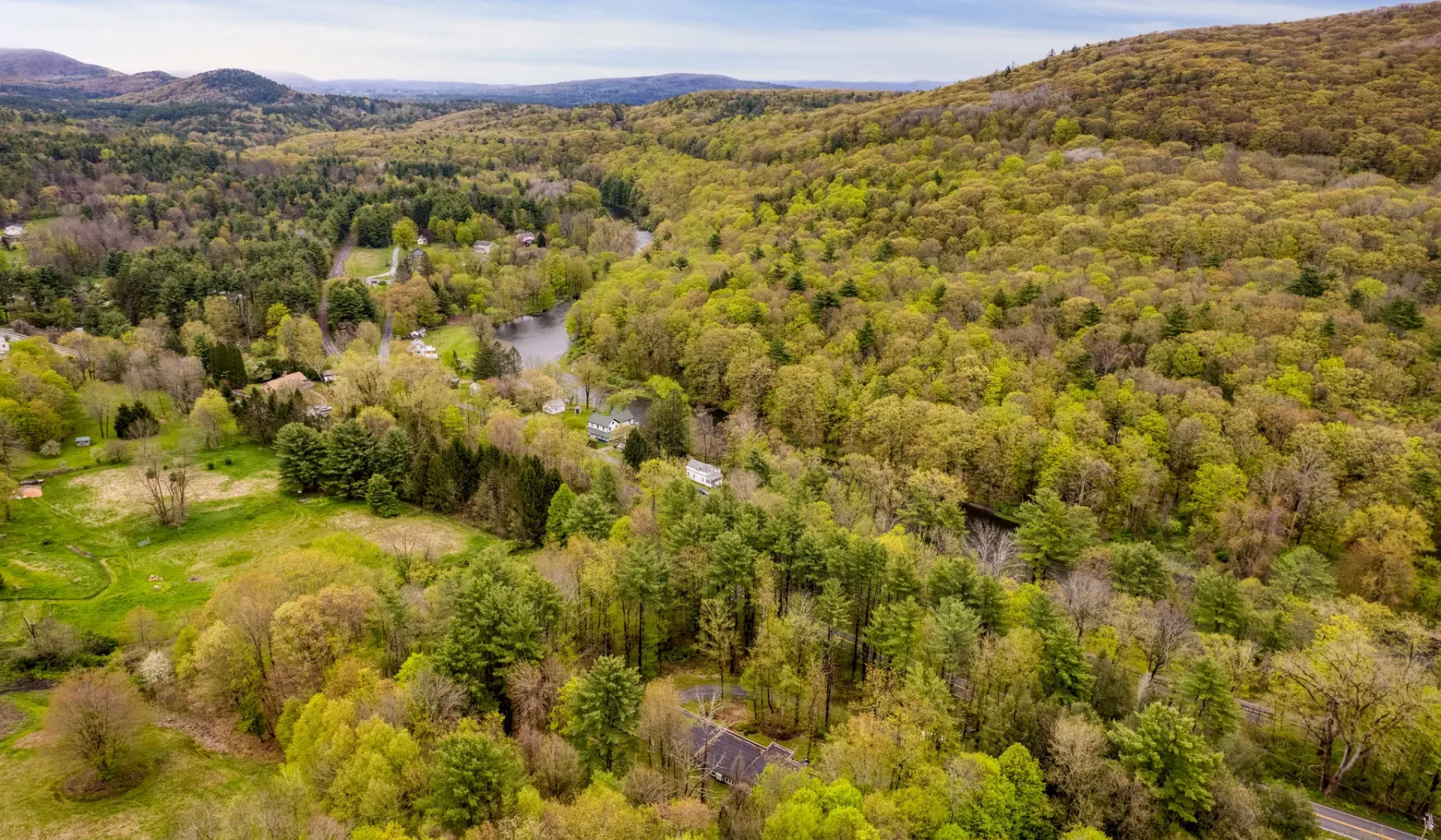 An aerial view of wooded hills and open green fields.