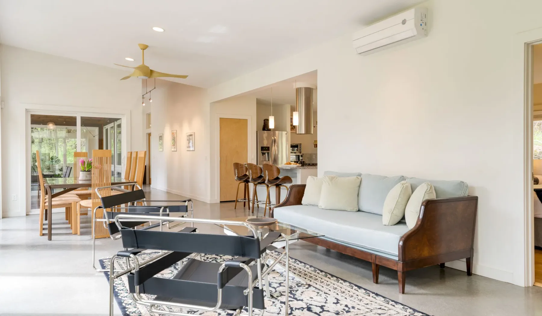A bright living and dining area with seating, a dining table, and glass doors.