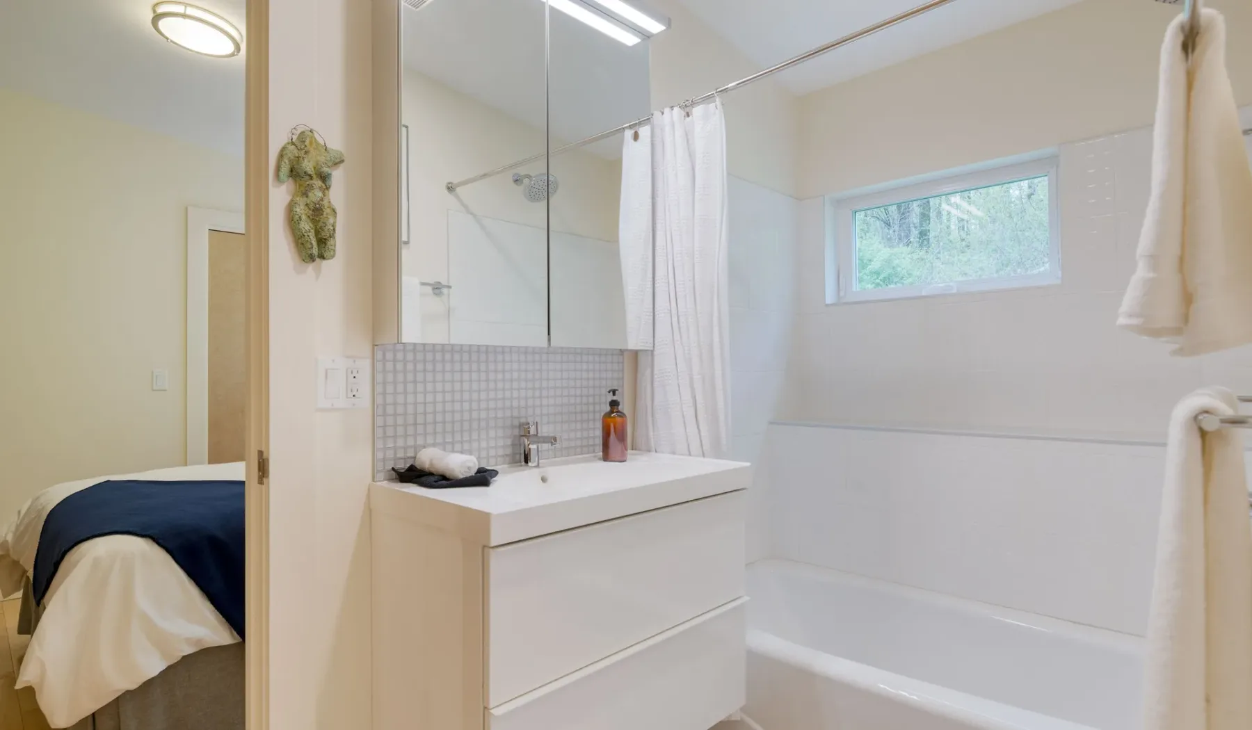 A bright bathroom with a vanity, mirror, and bathtub behind a shower curtain.