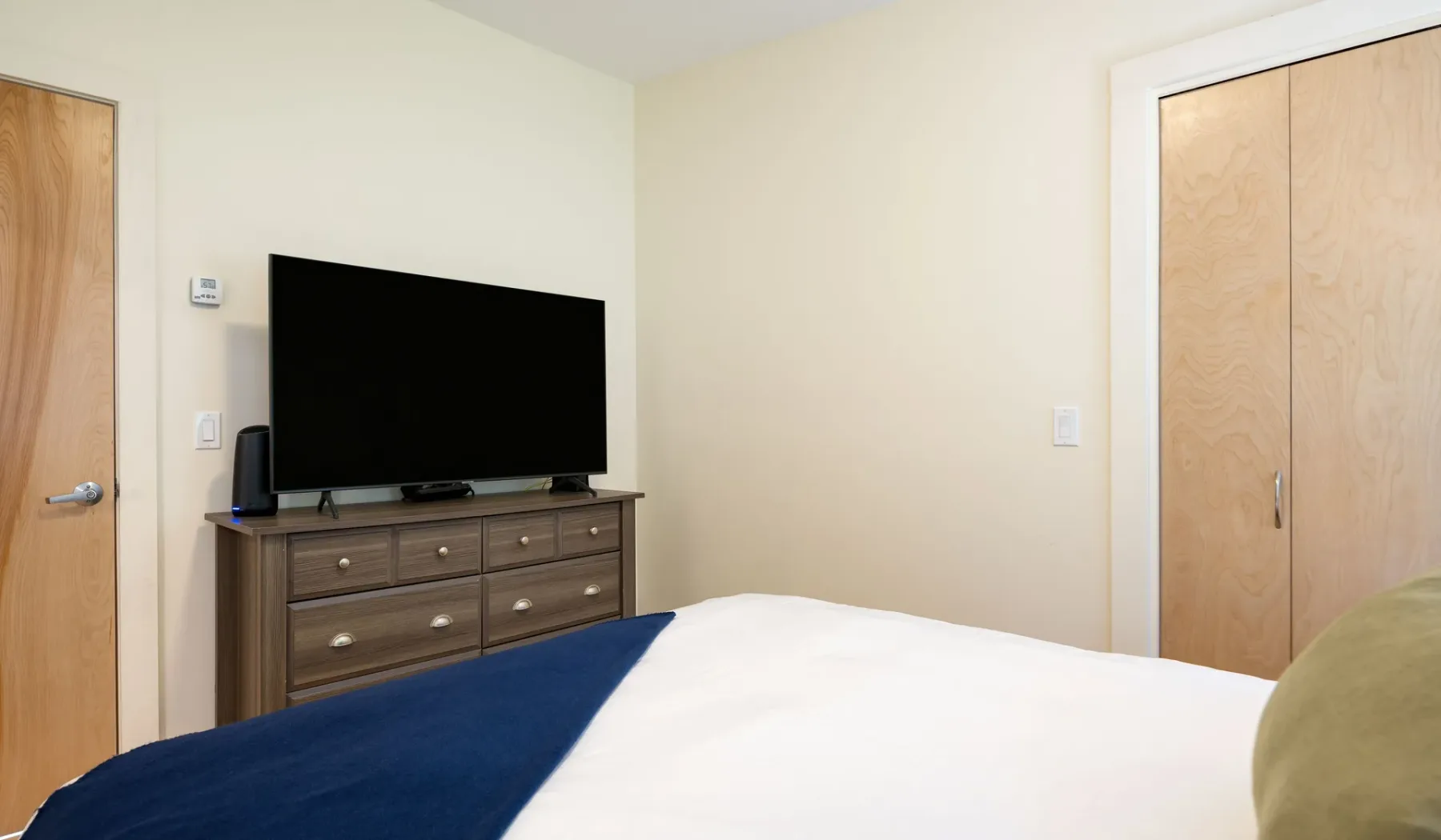 A bedroom with a bed, television, and wooden dresser.