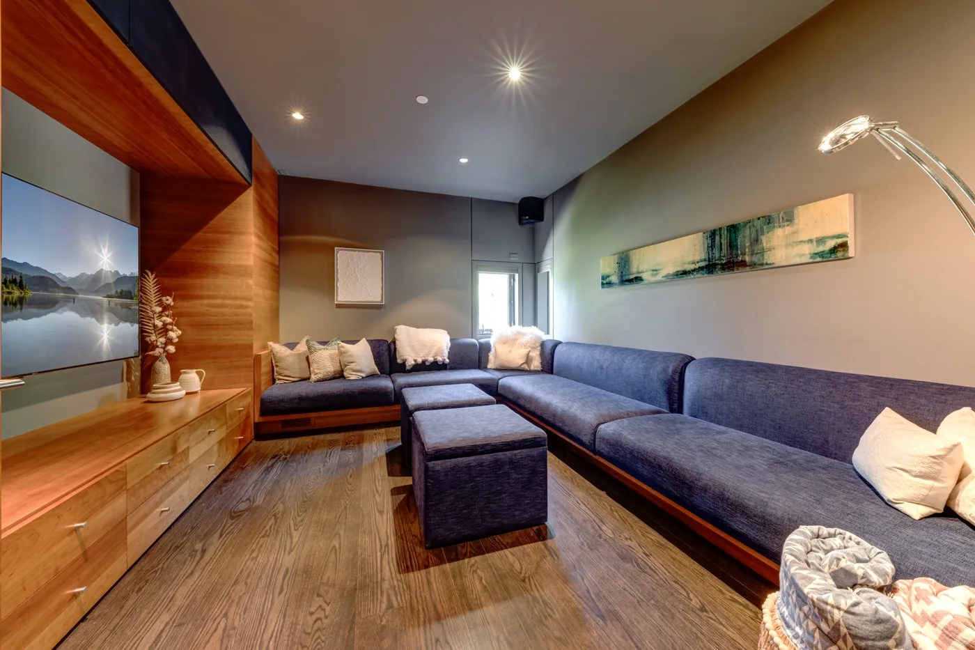 Una sala de estar con asientos seccionales, una mesa de centro y piso de madera.