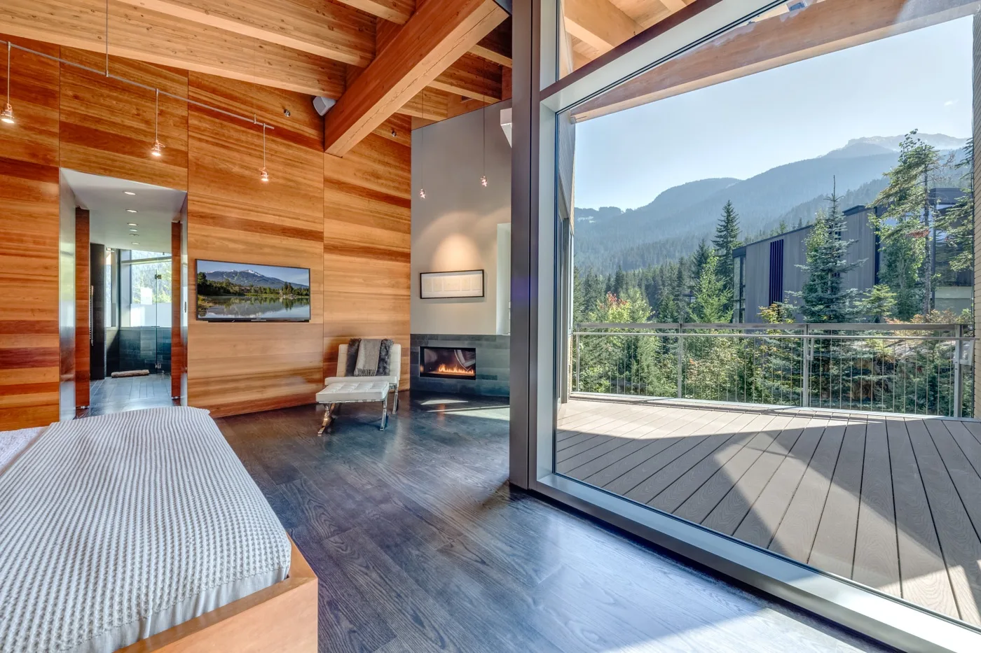 Un dormitorio revestido de madera da a una terraza con vistas a las montañas.